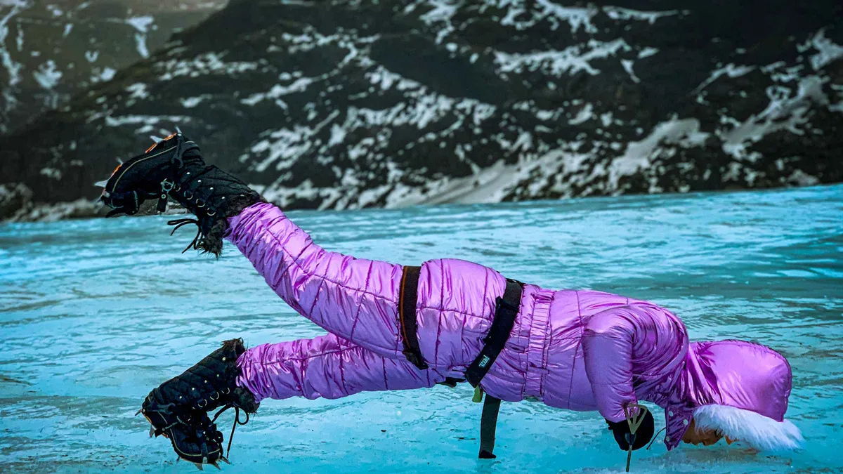 A rope of hikers in crampons crossing ridged grey-blue ice on a small-group Sólheimajökull glacier hike, South Iceland